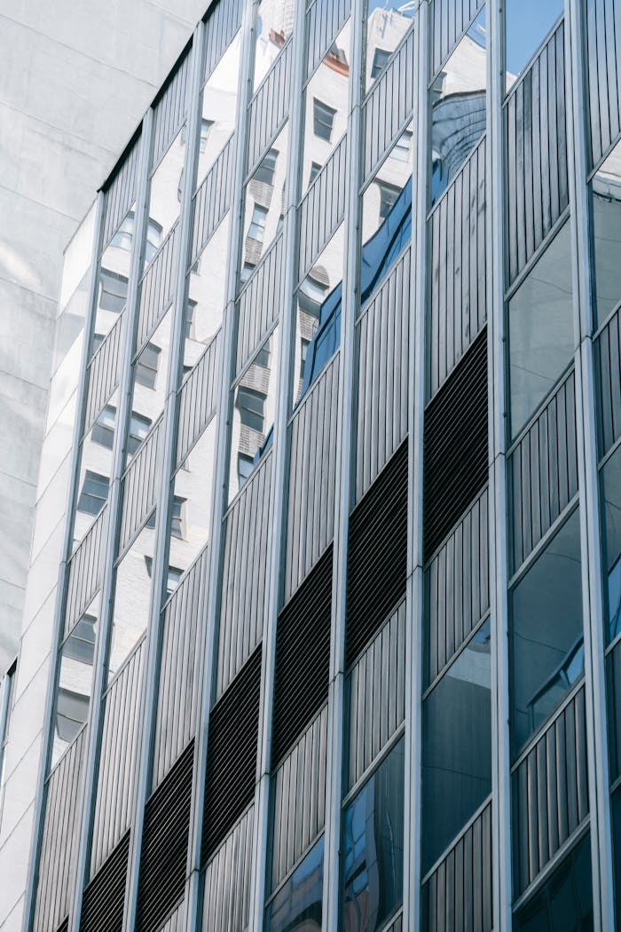 Exterior of modern multistory house with windows with reflections of buildings located on street in financial district of contemporary city